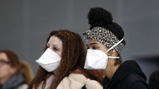 Women wear face masks at the Roissy Charles de Gaulle airport, north of Paris, Thursday, March 12, 2020.