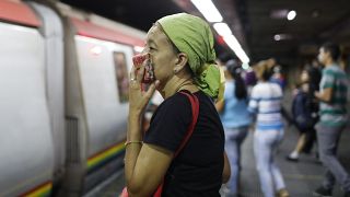 A woman covers her mouth and nose with a wash cloth on a subway platform in Caracas, Venezuela, Friday, March 13, 2020. 