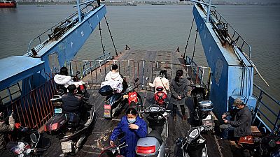 Passengers wearing face masks ride on a boat to cross the Yangtze river to Jiangzhou township in Jiujiang