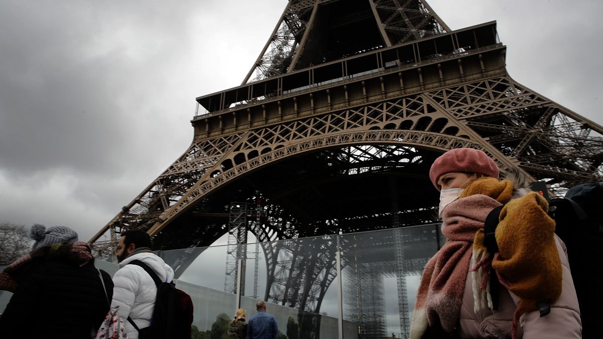 A woman wearing a mask walks pasts the Eiffel Tower closed after the French government banned all gatherings of over 100 people to limit the spread of virus COVID-19.