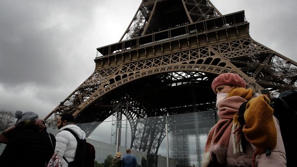 A woman wearing a mask walks pasts the Eiffel Tower closed after the French government banned all gatherings of over 100 people to limit the spread of virus COVID-19. A woman wearing a mask walks pasts the Eiffel Tower closed after the French government banned all gatherings of over 100 people to limit the spread of virus COVID-19.