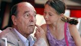 France's former president Jacques Chirac shows one of his cheek before a young girl gives him a kiss. FILE PHOTO August 2011