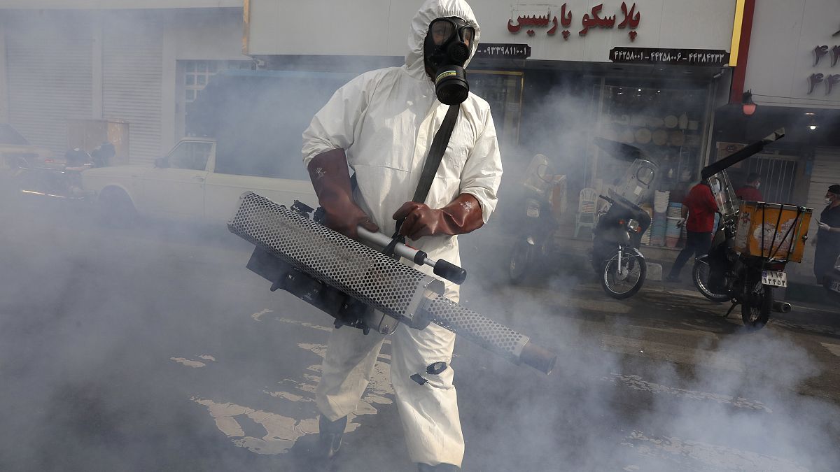 عامل من فرق الطوارئ يقوم برش مبيدات في شوارع العاصمة الإيرانية طهران