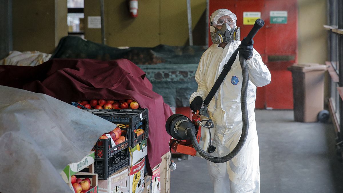 A man wearing protective gear sprays chemicals during the disinfection of a popular market, part of the efforts to limit the spread of Coronavirus, in Bucharest, March 2020