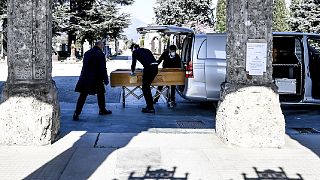 Undertakers carry a coffin out of a hearse at Bergamo's cemetery, northern Italy, Monday, March 16, 2020
