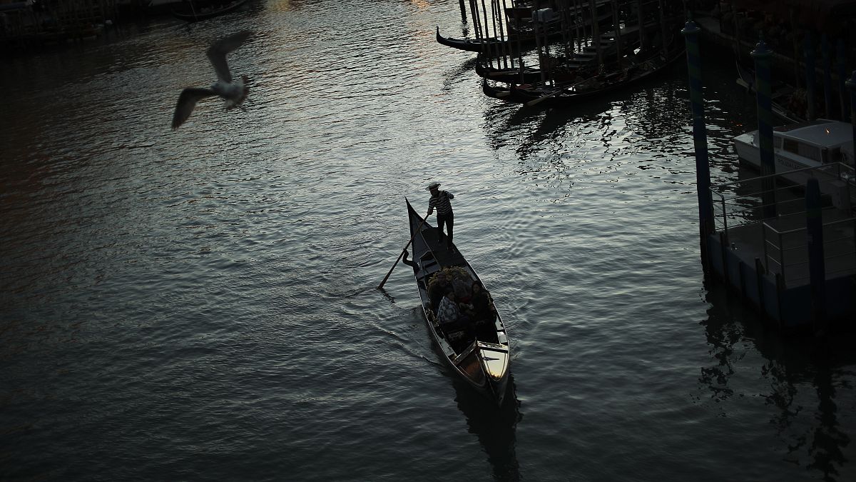 In this Feb. 28, 2020, file photo, a gondolier travels through the Grand Canal as the sun sets in Venice, Italy. 