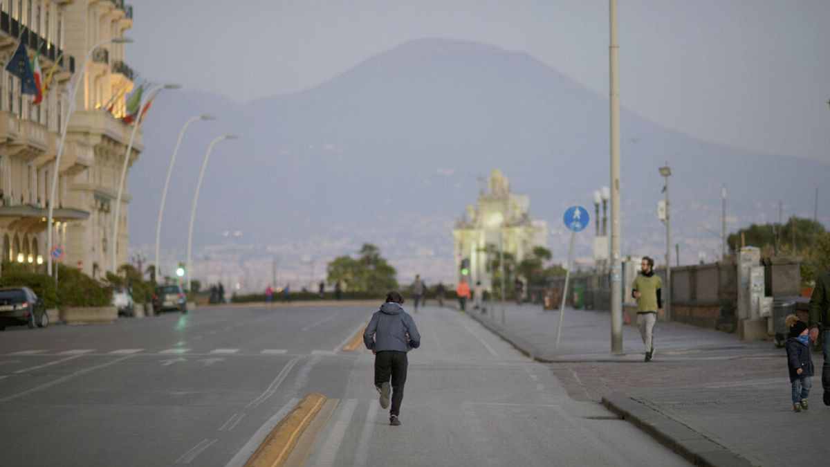 Un hombre haciendo deporte en las calles de Nápoles, frente al Vesubio, en plena cuarentena 