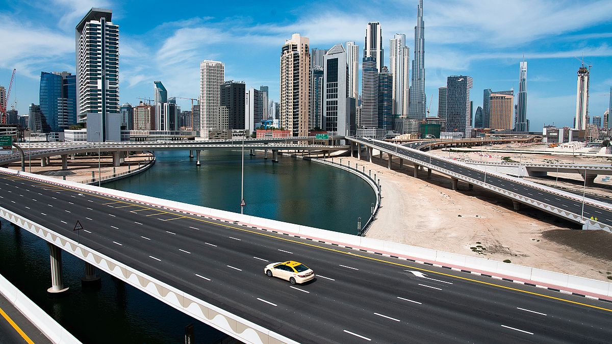 A lone taxi cab drives over a typically gridlocked highway with the Burj Khalifa, the world's tallest building, seen in the skyline behind it in Dubai, United Arab Emirates