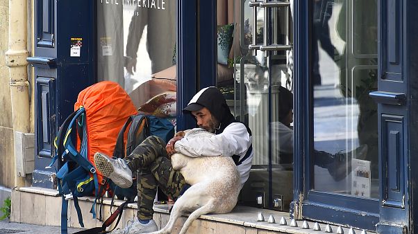 A homeless man hugs his dog as he sits along a deserted street on March 18, 2020 A homeless man hugs his dog as he sits along a deserted street on March 18, 2020