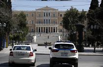 Police cars are parked in front of the empty Athens' main Syntagma square.