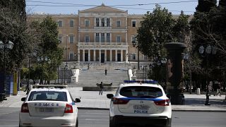 Police cars are parked in front of the empty Athens' main Syntagma square.