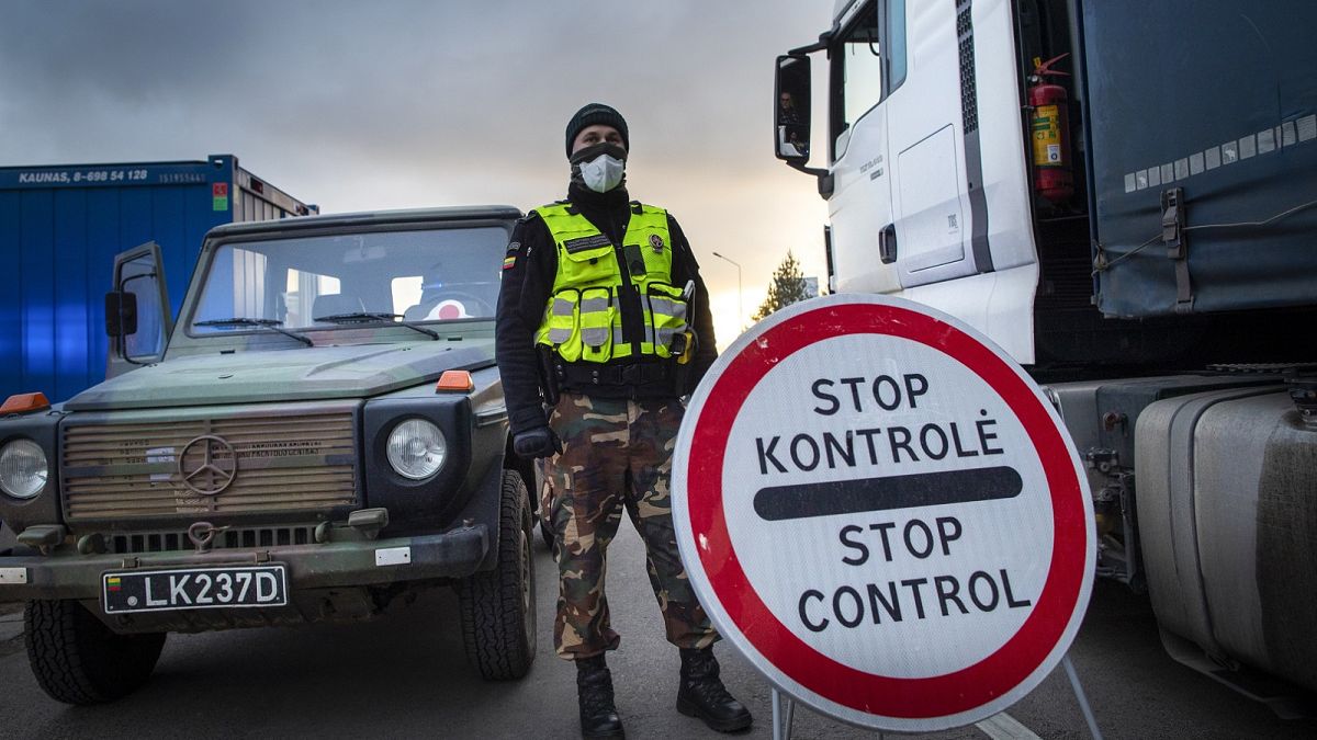 A Lithuanian border guard stands next to trucks stuck in traffic jams for 60 kilometers on Lithuanian side to enter Poland through Kalvarija-Budzisko check point