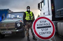 A Lithuanian border guard stands next to trucks stuck in traffic jams for 60 kilometers on Lithuanian side to enter Poland through Kalvarija-Budzisko check point