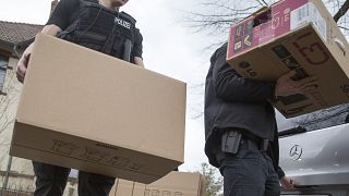 عنصران من الشرطة الألمانية ينقلان علبتين بعد مداهمة أحد البيوت التي كان يستخدمها التنظيم المتطرف