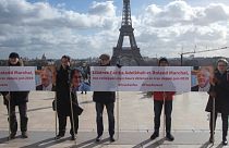 People gather with banners at Trocadero square in Paris, Tuesday, Feb. 11, 2020, calling for the release of French scientists Fariba Adelkhah et Roland Marchal.