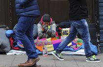 Pedestrians walk past a homeless man in the UK.