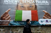 A man walks past a large billboard raising awareness to the measures taken by the Italian government to fight against the spread of the COVID-19.