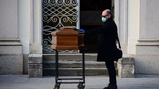A man touches the coffin of his mother during a funeral service in the closed cemetery of Seriate, near Bergamo, Lombardy, on March 20, 2020.