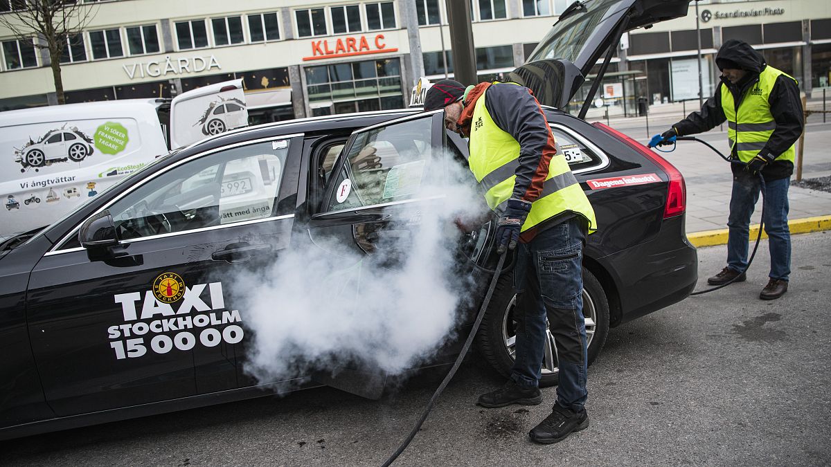 رجلان يعقمان سيارة أجرة بالعاصمة السويدية ستوكهولم منعا لانتاشر فيروس كورونا. 24/03/2020