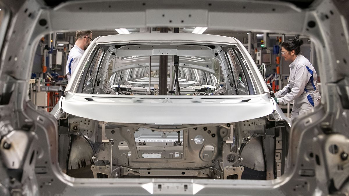 Workers complete an electric car ID.3 body at the assembly line during a press tour at the plant of the German manufacturer Volkswagen AG .