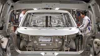 Workers complete an electric car ID.3 body at the assembly line during a press tour at the plant of the German manufacturer Volkswagen AG .