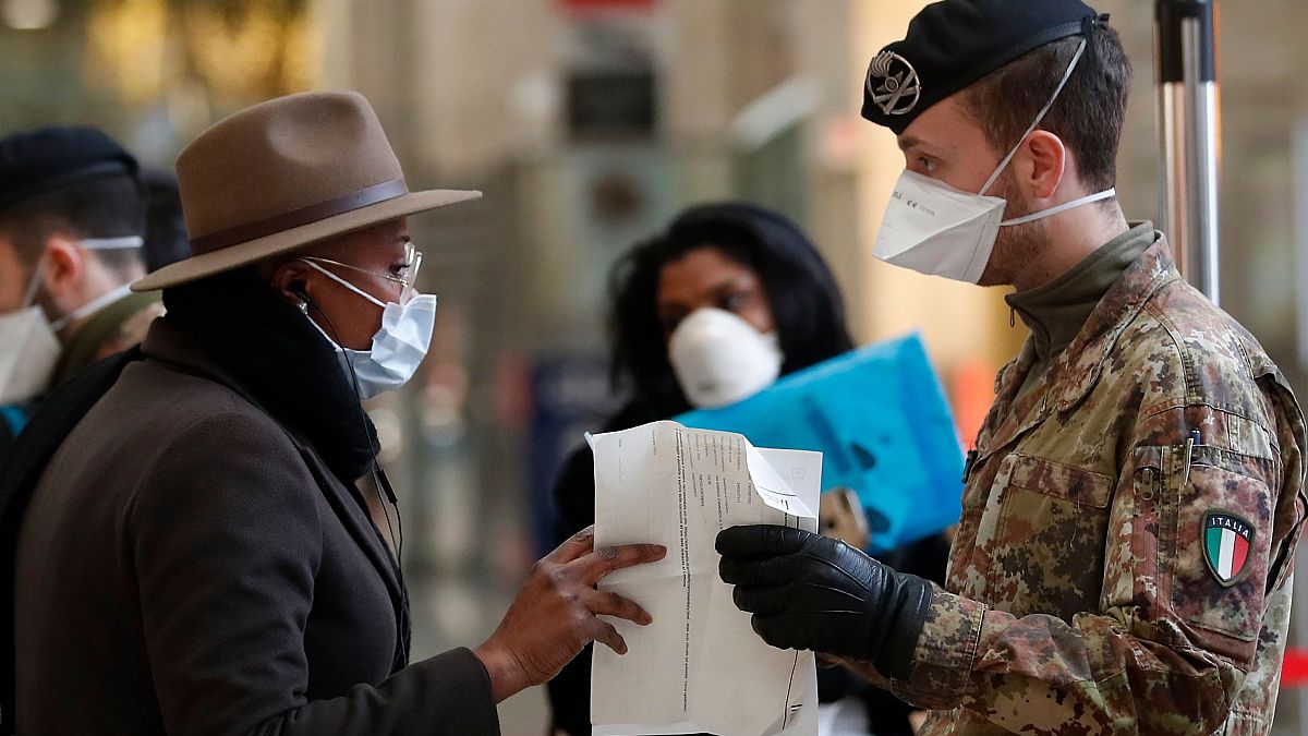 A soldier checks a passenger's papers at Milan's main train station, Italy