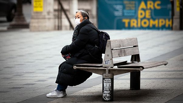 A woman wearing a face mask sits on a bench on the Champs-Elysees avenue in Paris, on March 16, 2020. A woman wearing a face mask sits on a bench on the Champs-Elysees avenue in Paris, on March 16, 2020.
