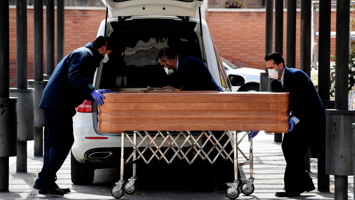 Le cercueil d'une victime du Covid-19 pris en charge par des agents funéraires, dans un cimetière de Madrid le 24 mars 2020.