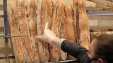 A vendor wearing a protective mask takes a baguette at a bakery in Paris, Monday, March 23, 2020.