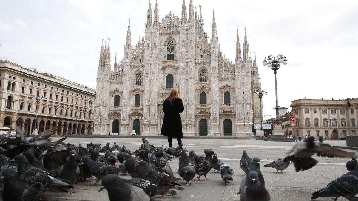 A woman stands in front of the Duomo cathedral, in downtown Milan, Italy.