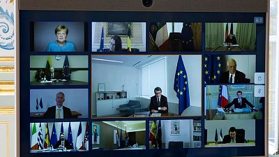 Members of the European Council are seen on the screen during a video conference call at the Elysee Palace in Paris, Thursday March, 26 2020. 