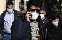 Un homme portant un masque de protection contre le nouveau coronavirus, parle sur son téléphone portable dans le centre de Téhéran, en Iran