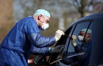 German doctor Michael Grosse swabs the throat of a car driver through the window on March 27, 2020 at a drive through testing point in Halle, eastern Germany.