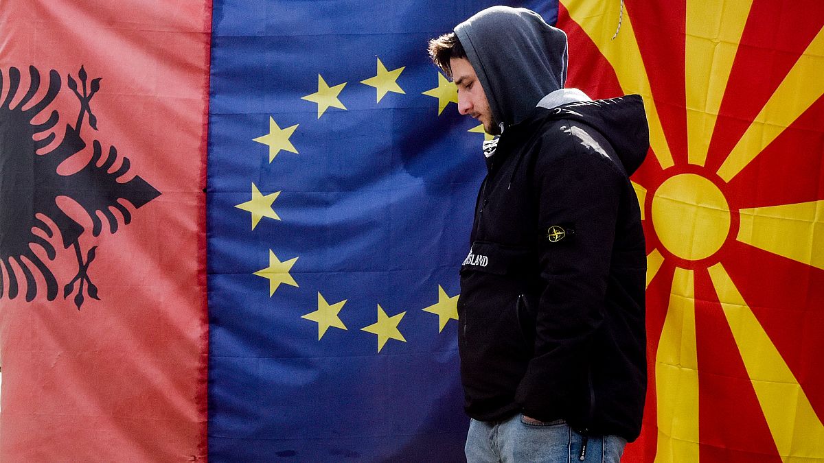 A man walks by Albanian EU and North Macedonia flags displayed in a bazaar in Skopje, on February 6, 2020.