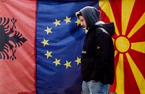 A man walks by Albanian EU and North Macedonia flags displayed in a bazaar in Skopje, on February 6, 2020.