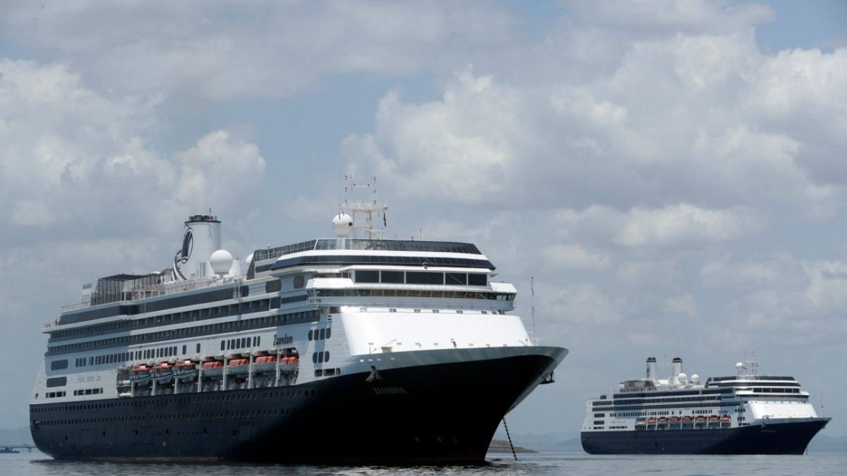 The Zaandam cruise ship, left, carrying some guests with flu-like symptoms, is anchored shortly after it arrived to the bay of Panama City, Friday, March 27, 2020.