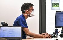 COVID-19'dan korunmak için yüz maskesi takan bir doktor, 2020 yılında Almanya'nın Essen kentindeki ofisinde bilgisayar başında çalışıyor.