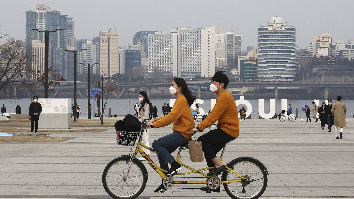 Güney Kore'nin başkenti Seul'de bisiklet süren maskeli çift. 