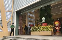 A store worker in protective suit waits for customers at a re-opened retail street in Wuhan in central China's Hubei province on Monday, March 30, 2020.