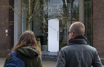 Two people look at the glass door which was smashed during a break-in at the Singer Museum in Laren, Netherlands, Monday March 30, 2020.