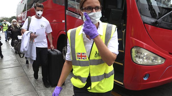 British travellers follow a British embassy employee before they are bused to the airport for flight home in Lima, Peru, Wednesday, March 25, 2020. (AP Photo/Martin Mejia) British travellers follow a British embassy employee before they are bused to the airport for flight home in Lima, Peru, Wednesday, March 25, 2020. (AP Photo/Martin Mejia)