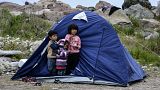 Children stand outside a tent in the village of Petra on the northeastern Aegean island of Lesbos, Greece, Friday, March 27, 2020