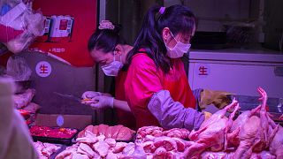 Employees wear face masks as they work at a poultry stall at a market in Beijing, Saturday, March 14, 2020