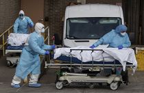 Medical personnel wearing personal protective equipment remove bodies from a medical centre in New York, 2020.