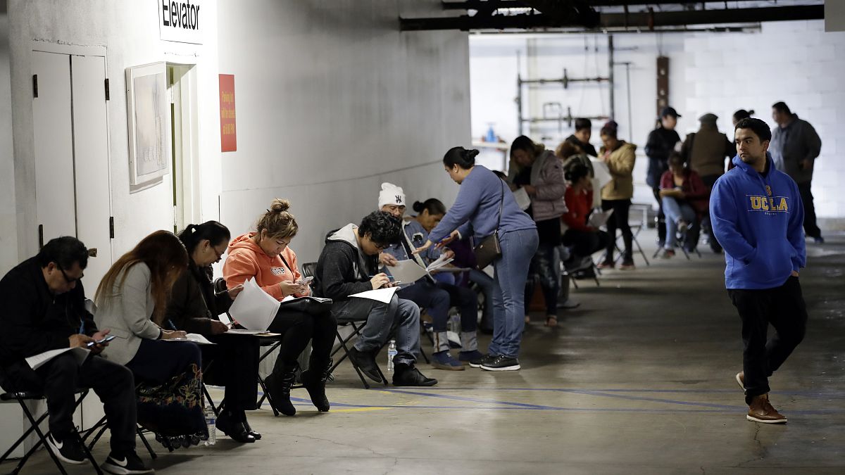 In this March 13, 2020 file photo, unionised hospitality workers wait in line in a basement garage to apply for unemployment benefits in Los Angeles