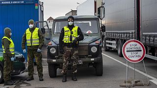 Lithuanian border guards stand next to trucks stuck in traffic jams