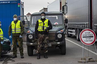 Lithuanian border guards stand next to trucks stuck in traffic jams