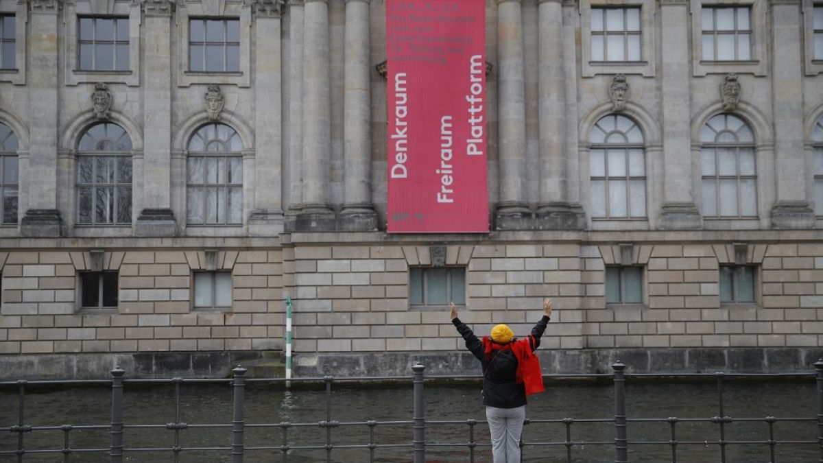 A woman stretches at the river Spree on the other side of the Bode museum at the Museum island in Berlin, on April 2, 2020. (Photo by Odd ANDERSEN / AFP)
