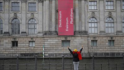 A woman stretches at the river Spree on the other side of the Bode museum at the Museum island in Berlin, on April 2, 2020. (Photo by Odd ANDERSEN / AFP)