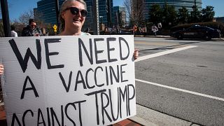 A protestor holds a sign in front of the Centers for Disease Control and Prevention headquarters on Friday, March 6, 2020 in Atlanta, Georgia.